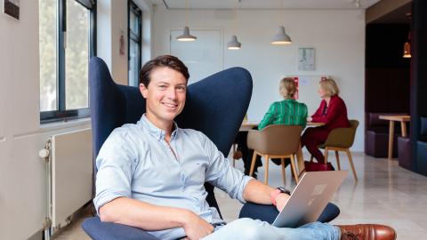 Collega in een stoel met een laptop op schoot.