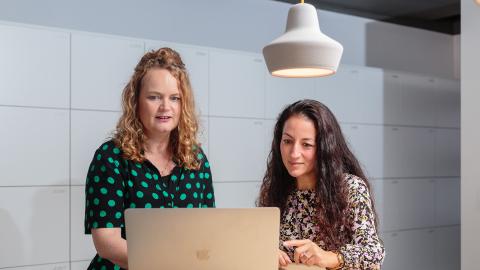 Twee collega's kijken naar het scherm van een laptop