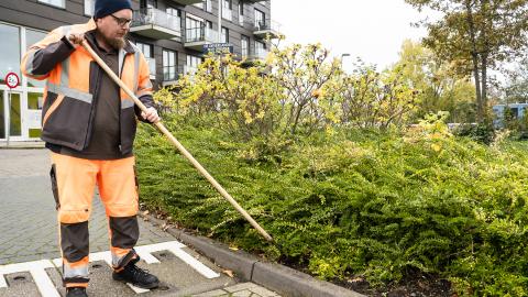 Een collega van de buitendienst is buiten aan het schoffelen