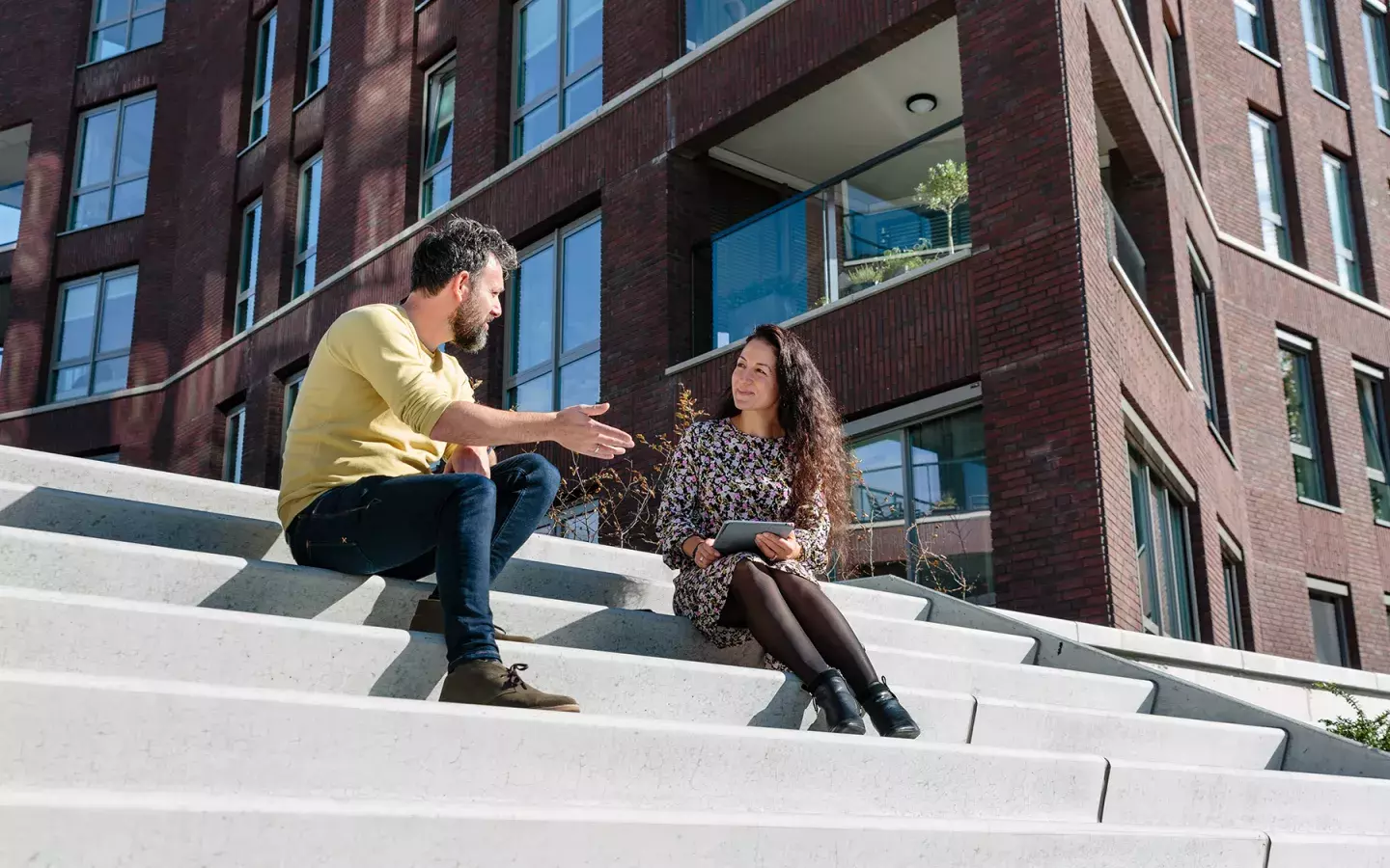 Twee collega's zittend in gesprek buiten op een trap